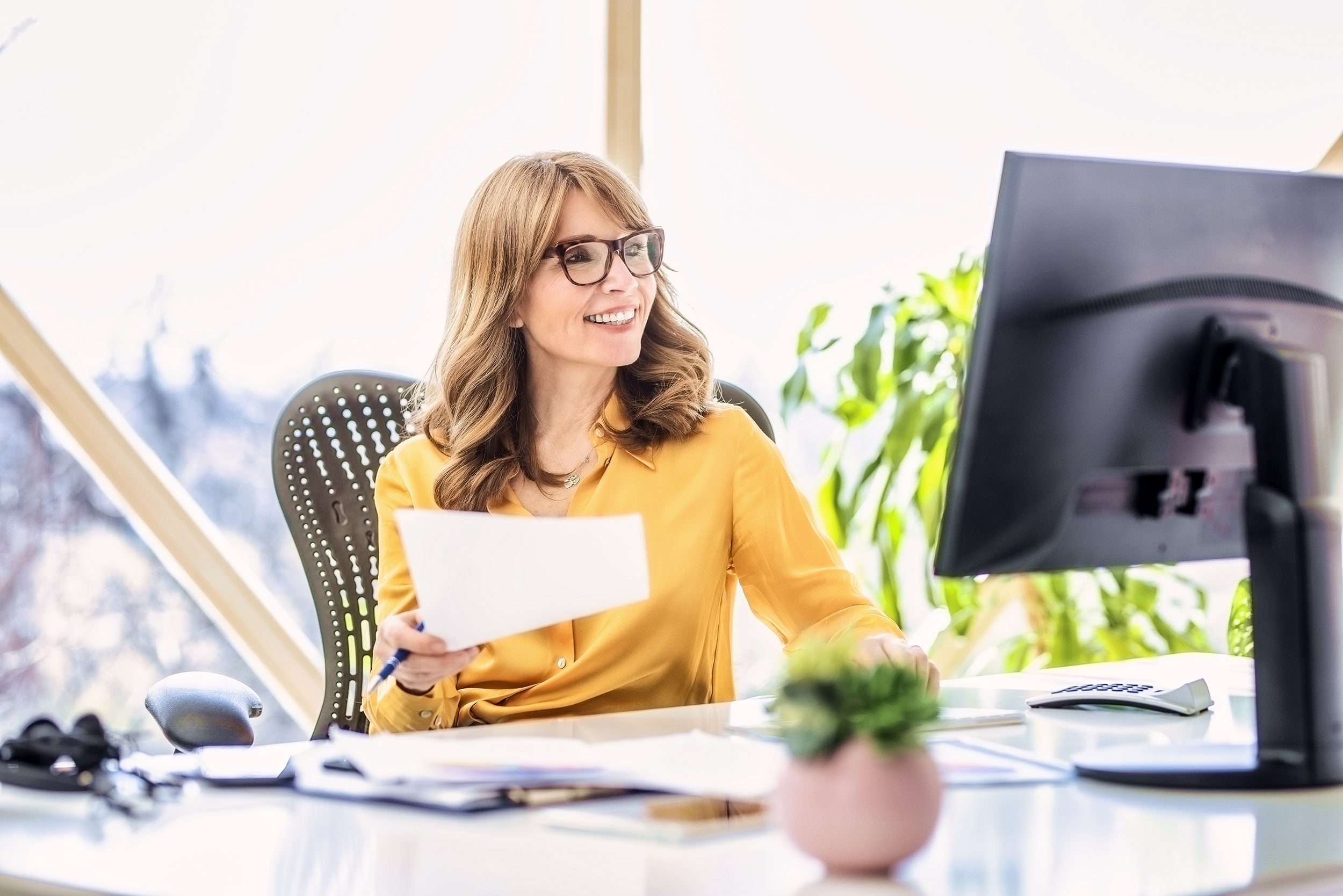 Shot of happy mature businesswoman sitting at office desk