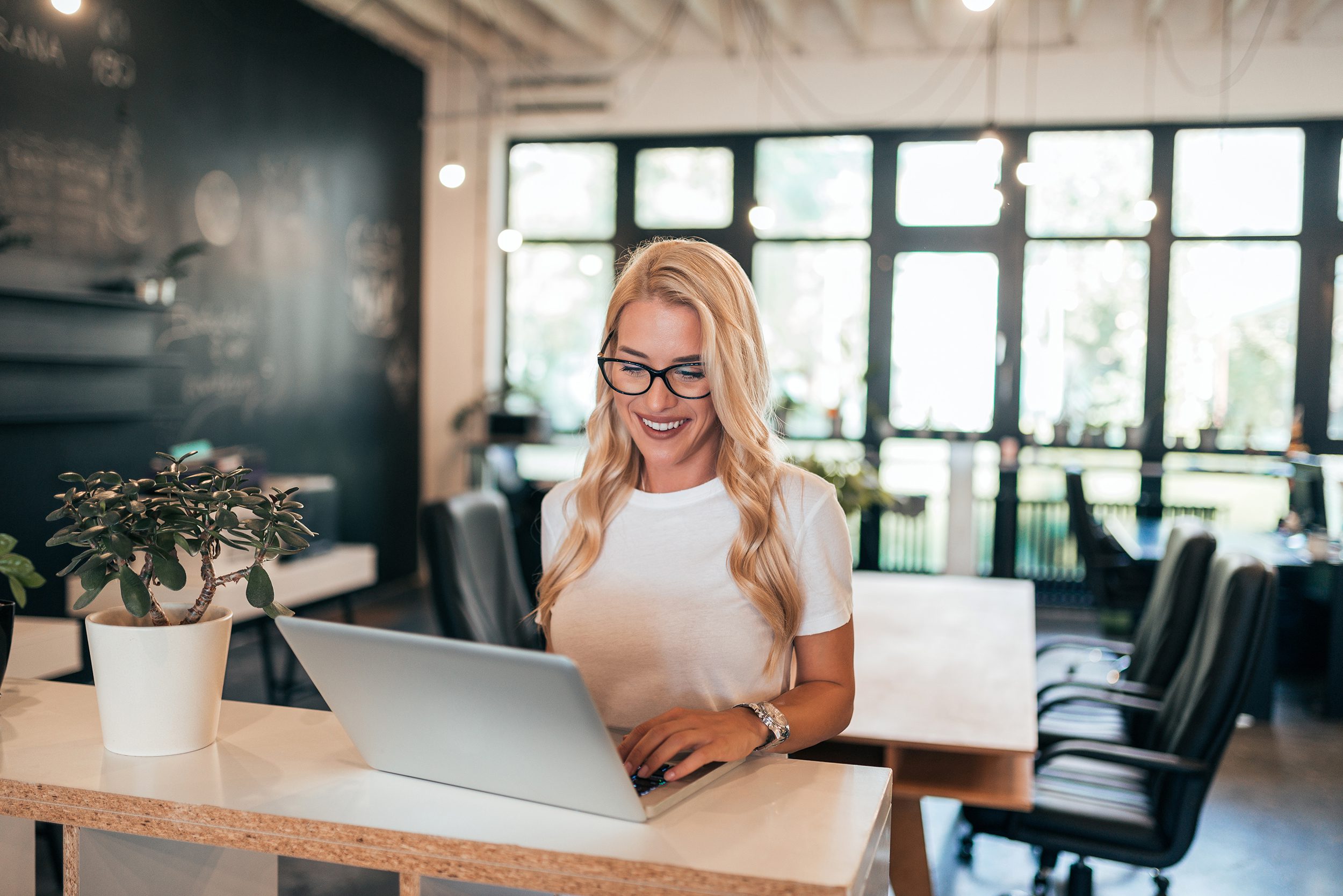 Successful female entrepreneur working on laptop in modern office.