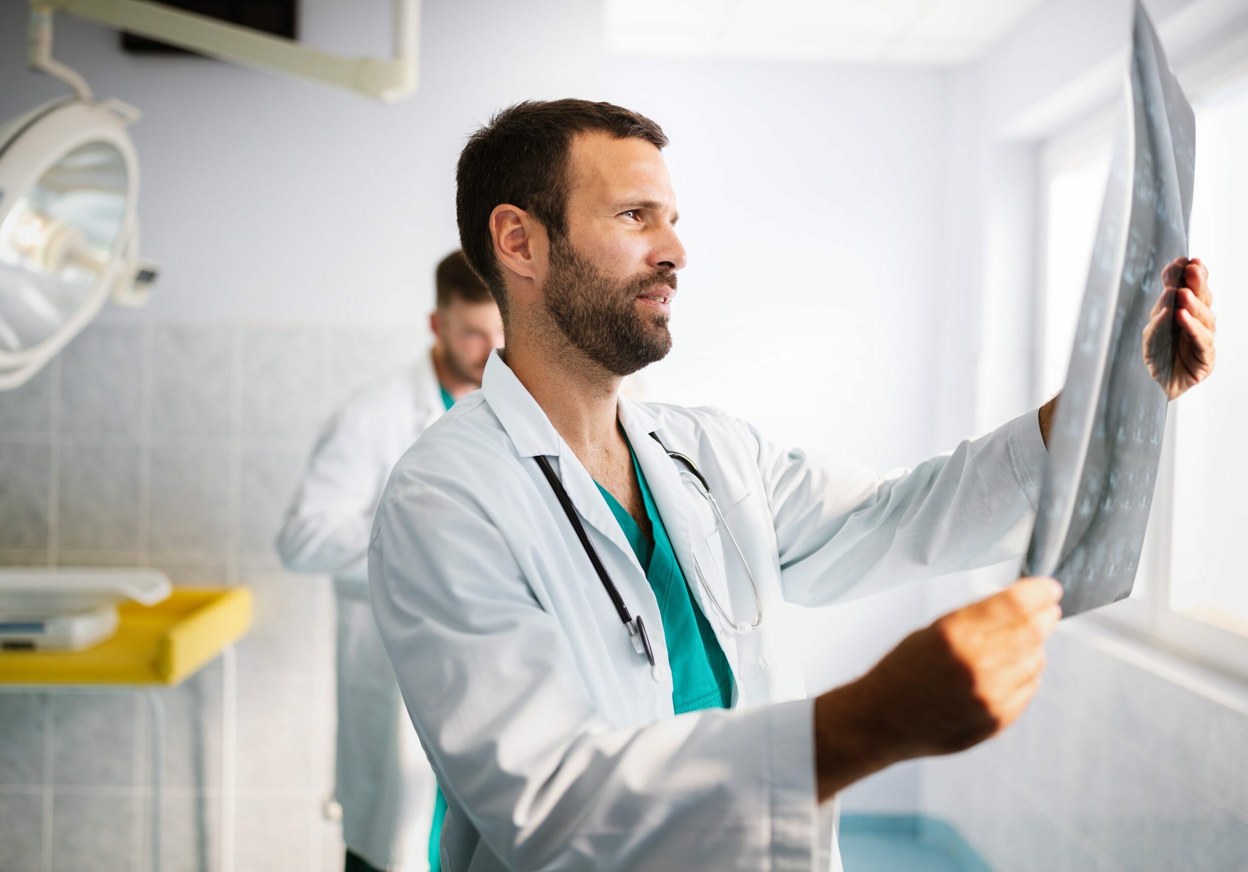 Portrait of handsome young doctor checking X-Ray in hospital to make diagnosis