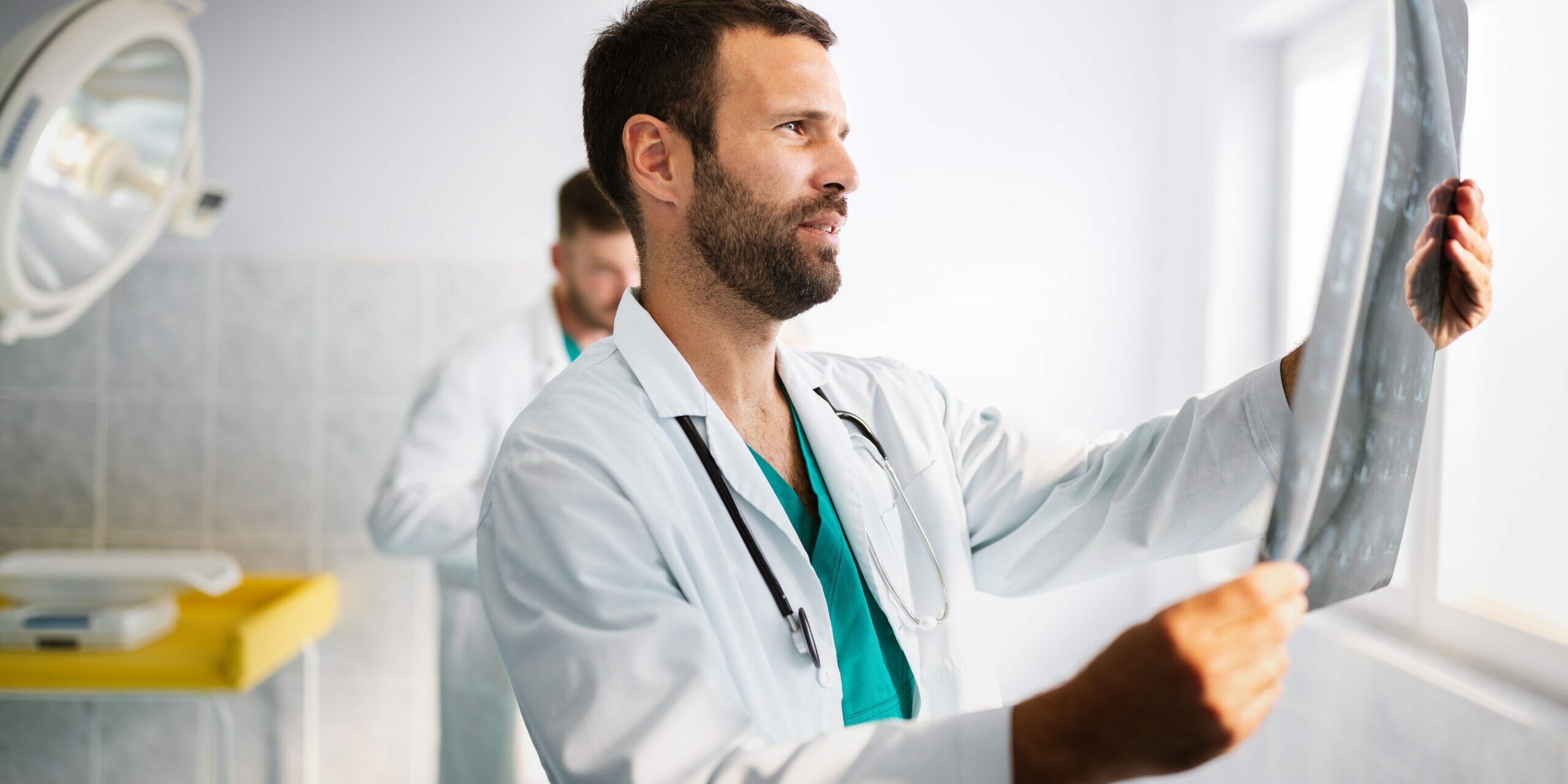 Portrait of handsome young doctor checking X-Ray in hospital to make diagnosis