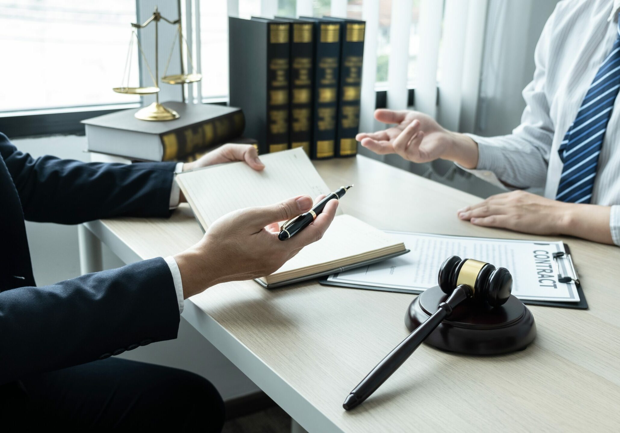 Male lawyer working on documents contract papers of the important case with the business customer and wooden gavel, brass scale in office.