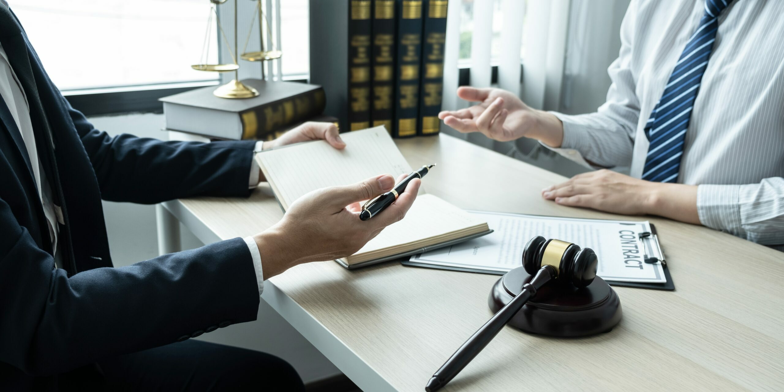 Male lawyer working on documents contract papers of the important case with the business customer and wooden gavel, brass scale in office.