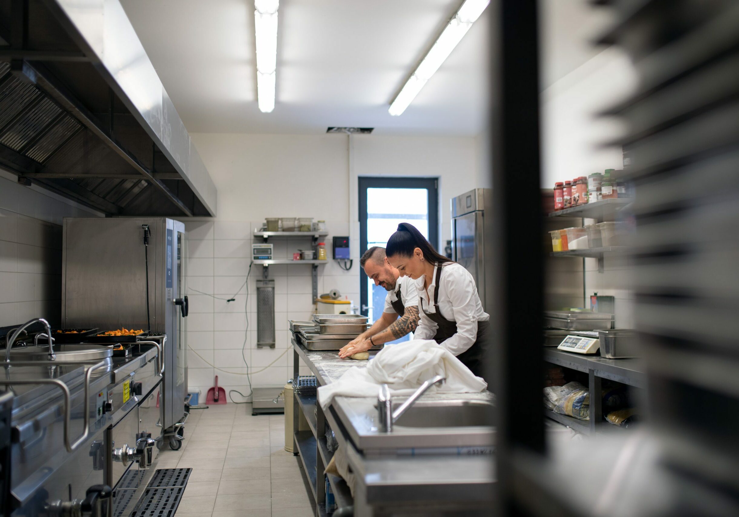 A chef and cook working on their dishes indoors in restaurant kitchen.