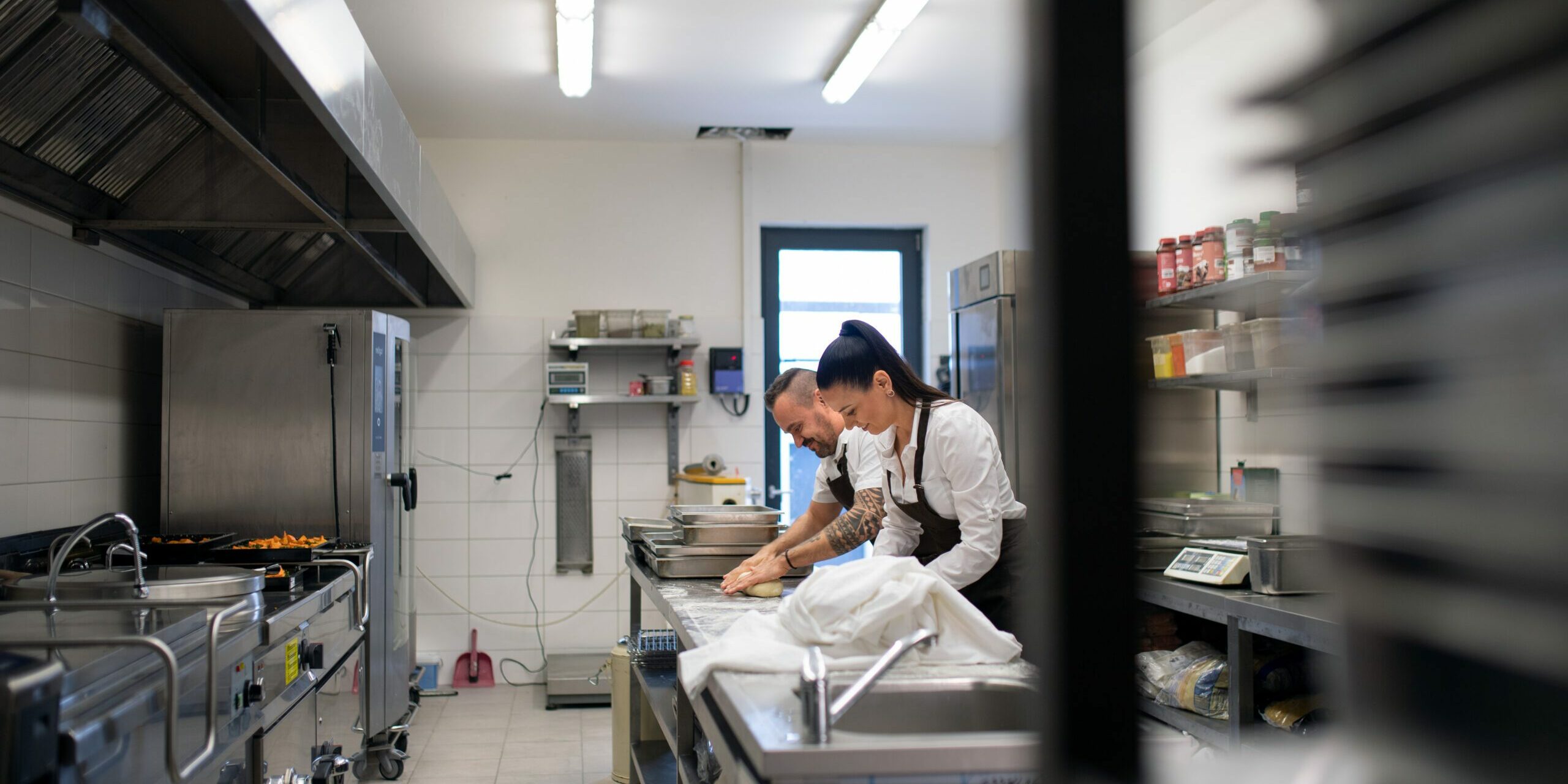A chef and cook working on their dishes indoors in restaurant kitchen.
