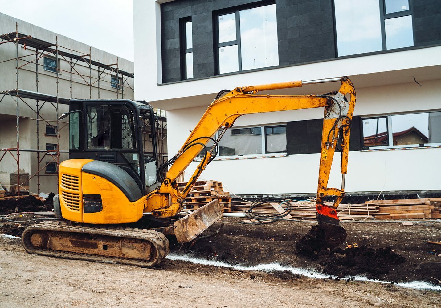 Mini heavy duty excavator moving earth for foundation building. Industrial machinery on construction site,