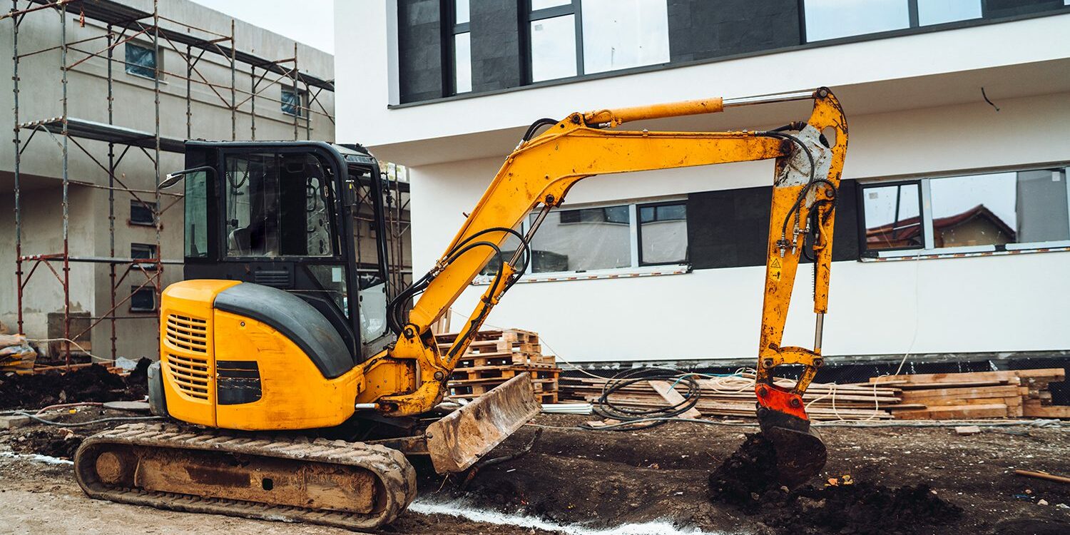 Mini heavy duty excavator moving earth for foundation building. Industrial machinery on construction site,