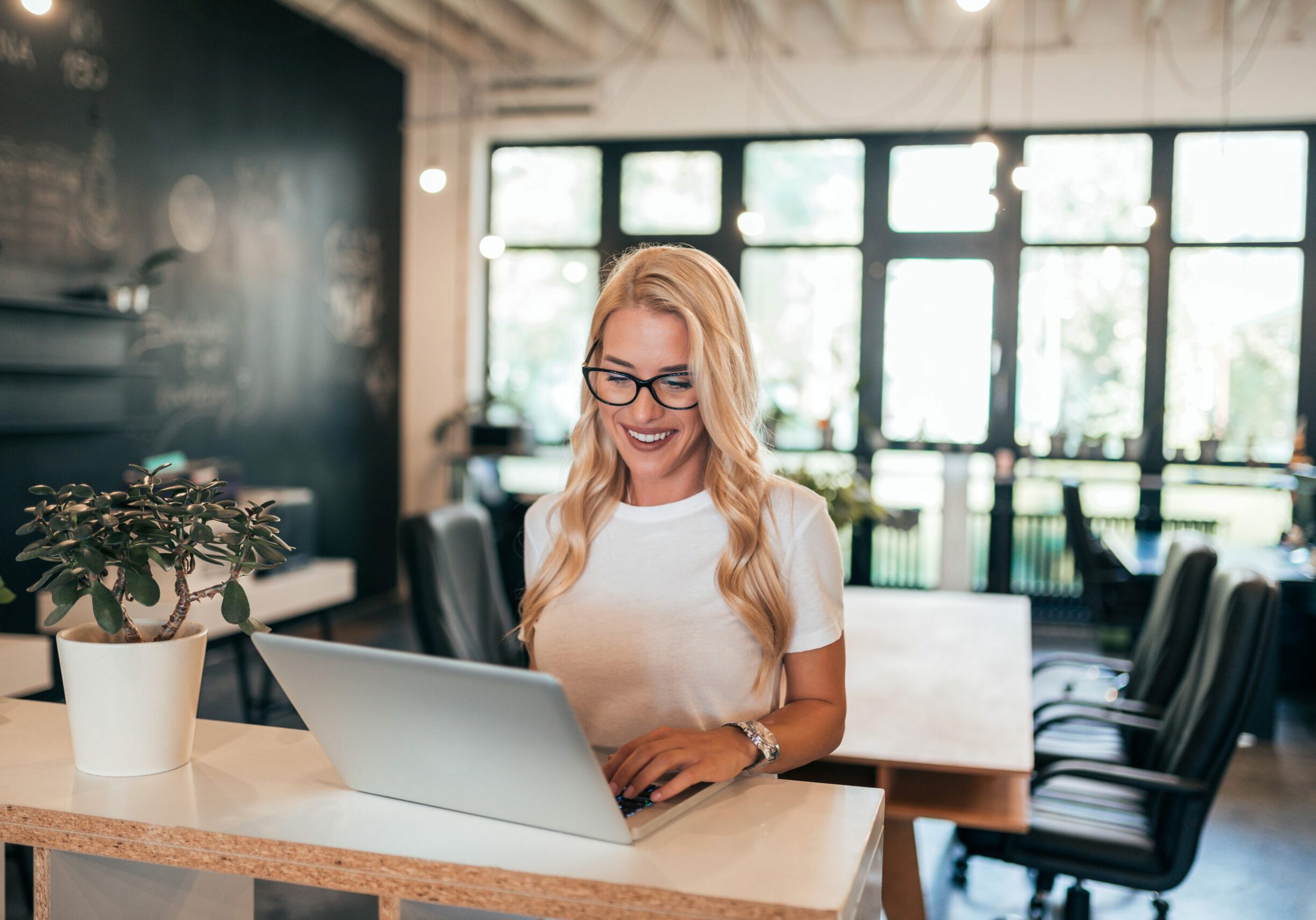 Successful female entrepreneur working on laptop in modern office.