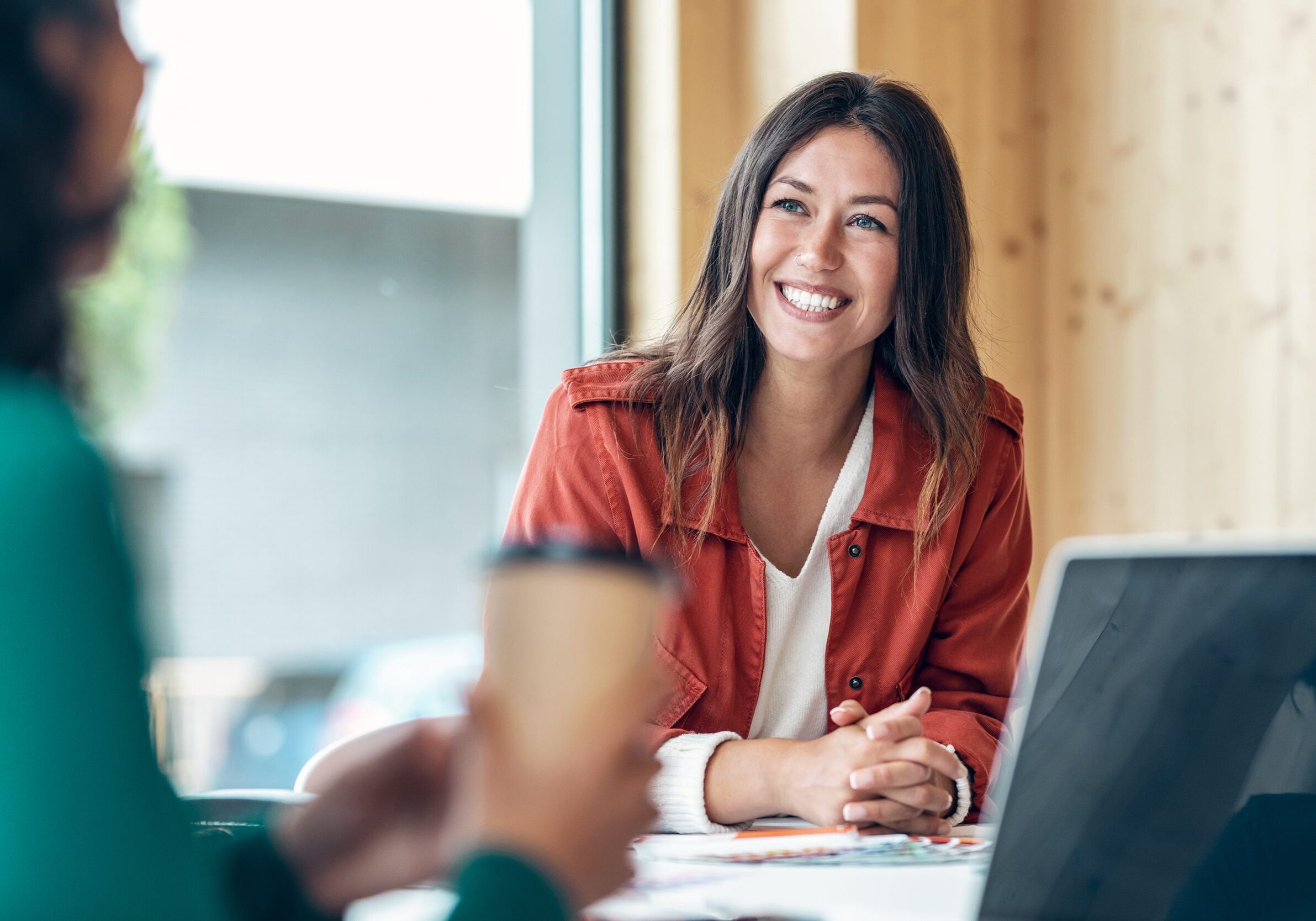 Shot of smiling young business woman listening her partner on coworking space.