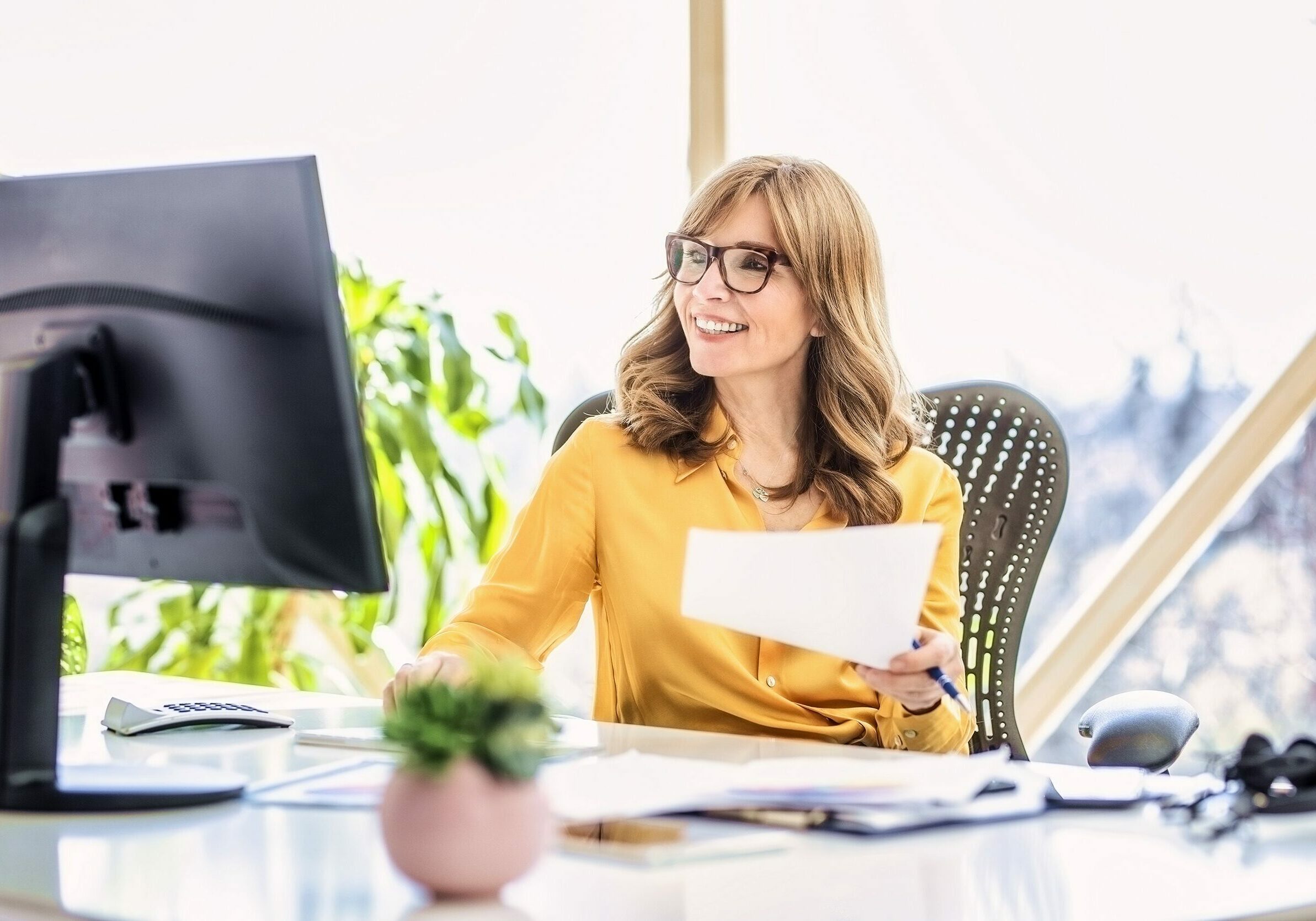 Shot of happy mature businesswoman sitting at office desk