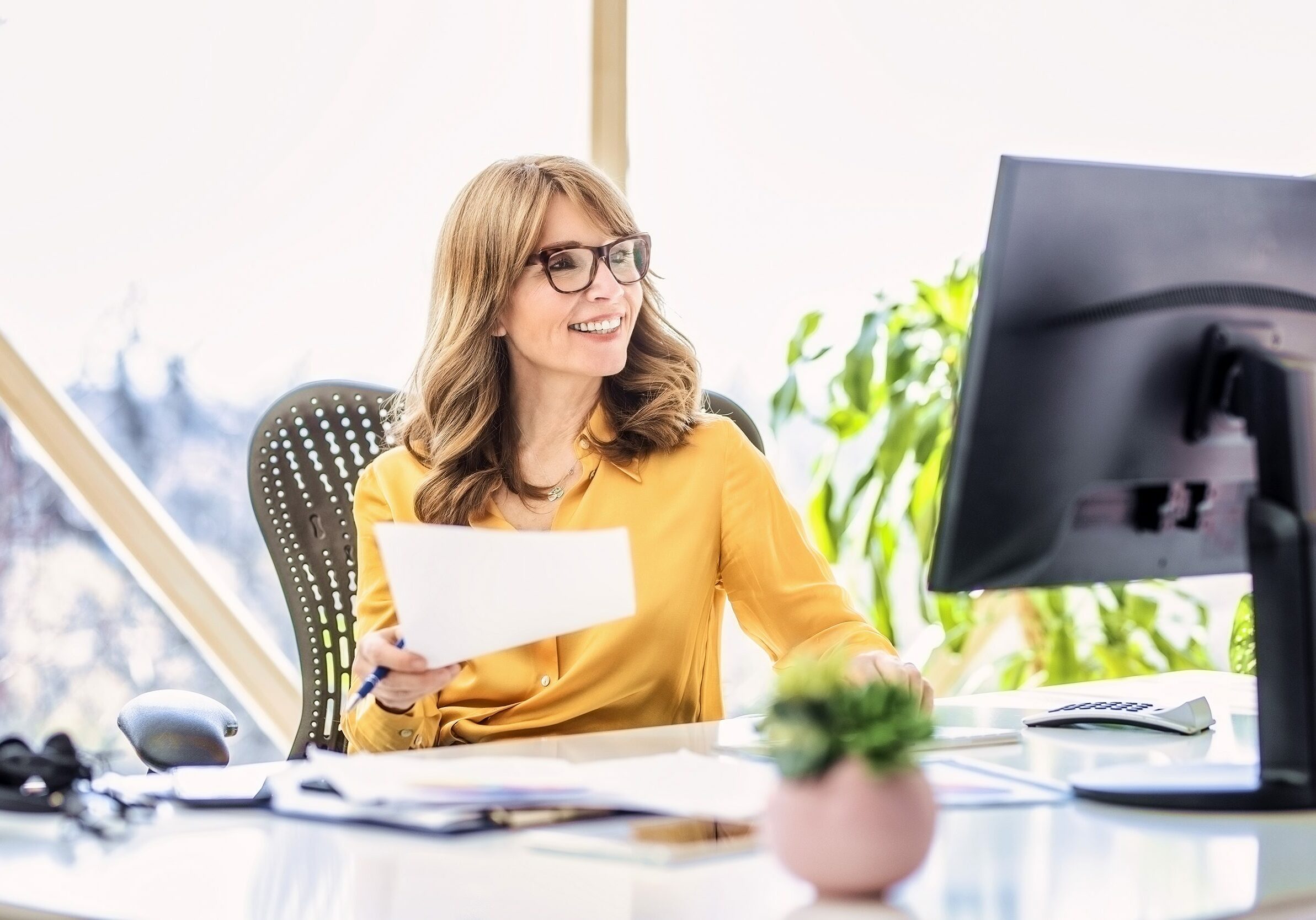 Shot of happy mature businesswoman sitting at office desk